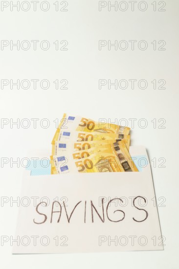 Envelope containing fifty euro banknotes and the word savings represents the concept of