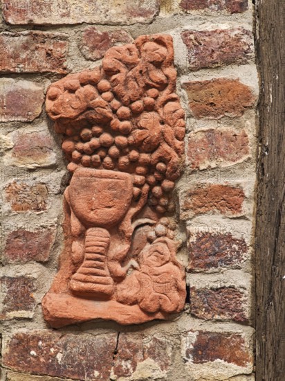 Clay work in house wall, pottery, handicraft, art, grapes, wine glass, red clinker, wooden beams,
