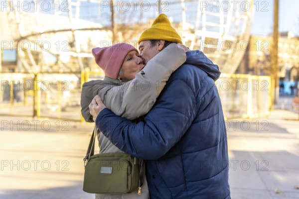 Elderly couple sharing a tender kiss and hug in a festive winter cityscape, celebrating love and