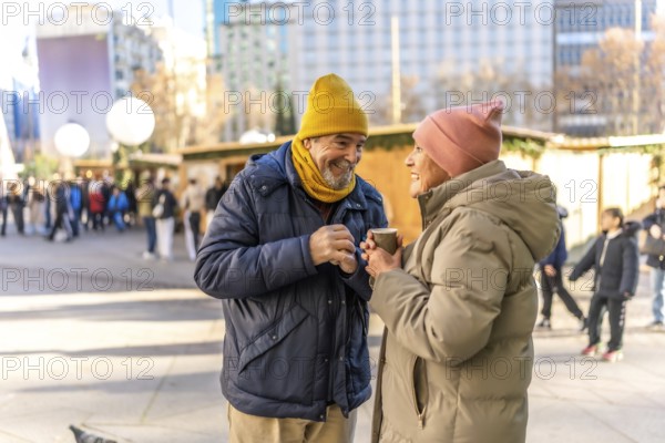 Smiling senior couple holding hot beverages and enjoying each other's company at a bustling