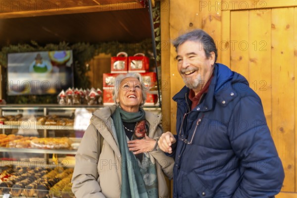 Cheerful senior couple smiling and enjoying the festive atmosphere at a christmas market in a