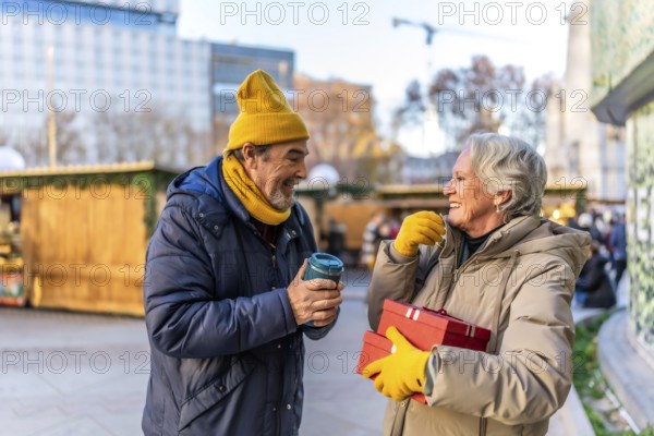 Elderly couple exchanging christmas presents and enjoying a hot beverage at a traditional christmas