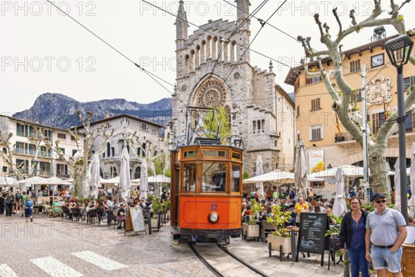 Old vintage train on the city square outside the church between outdoor restaurants and tourists,
