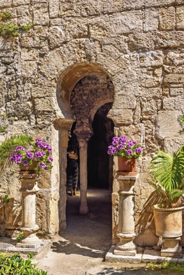 Flowers on pedestals at an opening into the Arab baths old building with oriental architecture,