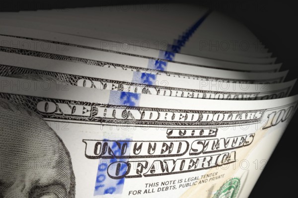 Spot lit abstract close-up angle of U.S. 100 dollar bills isolated on a black background