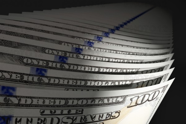 Spot lit abstract close-up angle of U.S. 100 dollar bills isolated on a black background