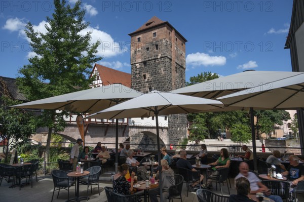 Historic water tower built around 1325, in front a café on the Pegnitz, Nuremberg, Middle