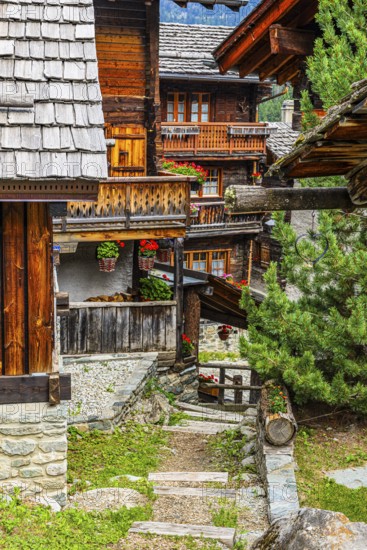 Winding wooden houses with flower-decorated balconies in the historic centre of Grimentz, Val