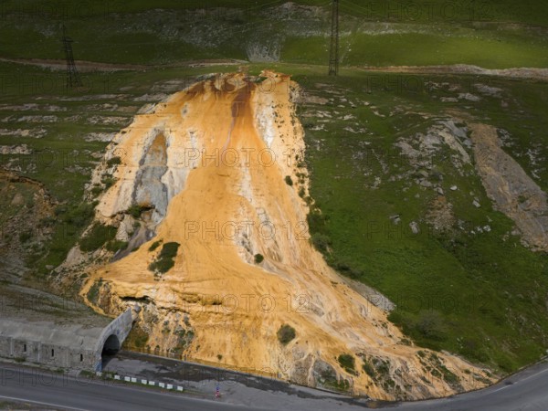 A hill with a distinctive orange rock formation next to a road with a bridge, aerial view, Bidara