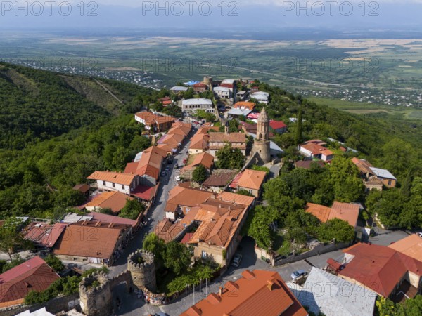 Surrounded by hills lies a picturesque village with tiled roofs and a church overlooking the