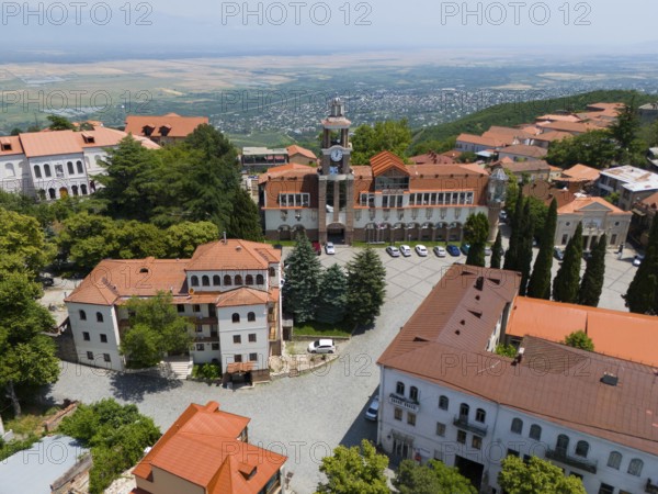 A square with a tower and traditional buildings framed by a panoramic view, aerial view, Sighnaghi,