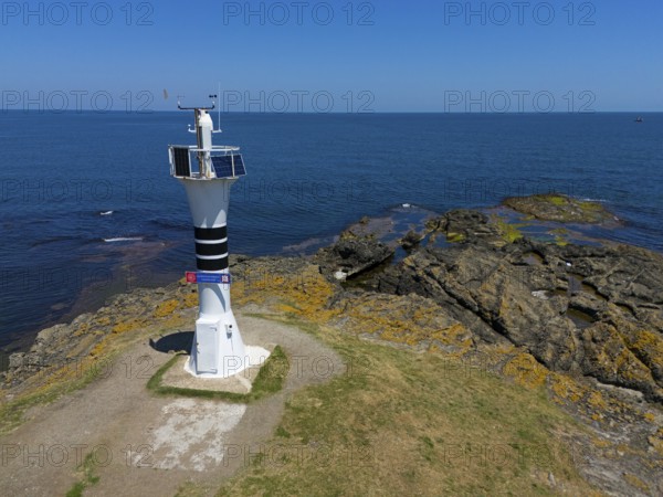 Close-up of a lighthouse on a rocky coast with the wide sea and blue sky, aerial view, Yason Burnu