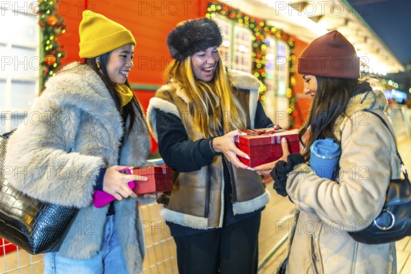 Three joyful women exchanging christmas gifts while enjoying the festive atmosphere of a