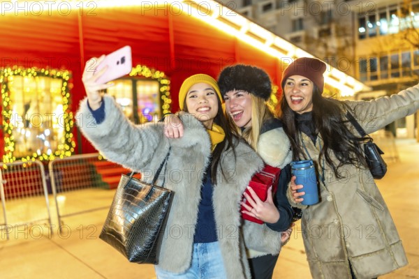 Three happy female friends taking a selfie at a christmas market, enjoying the festive atmosphere