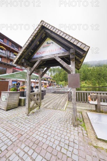 Wooden roofing at a boat hire with people and surrounding buildings, Mummelsee, Seebach, Ortenau