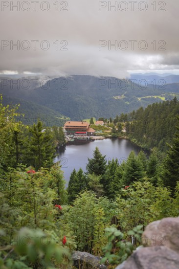 View over a lake with mountains and houses under a cloudy sky, Mummelsee, Seebach, Ortenau