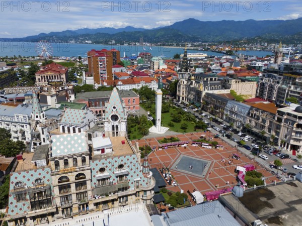 Historic architecture with large square, surrounded by mountains near the coast, aerial view,