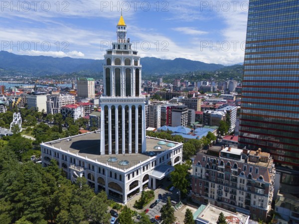 Tall building in a city with mountain backdrop and blue sky, aerial view, Sheraton Hotel, Batumi,