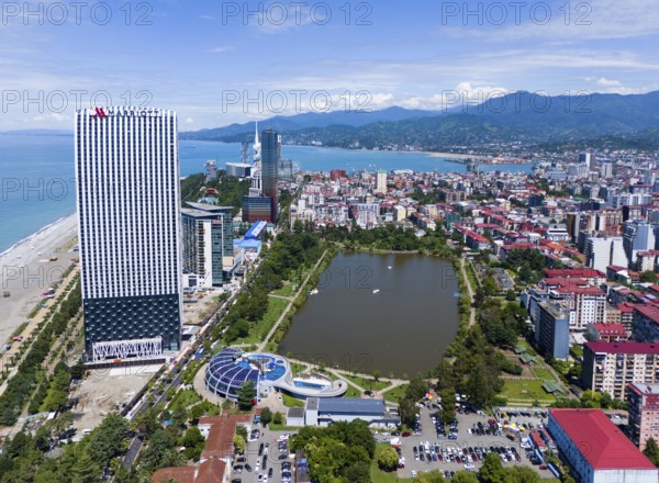 High-rise buildings on the beach with park, lake and mountains in the background, aerial view,