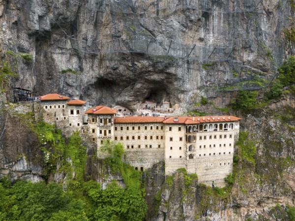 Monastery built into the rock with red roofs, surrounded by steep rock faces, aerial view, Sumela