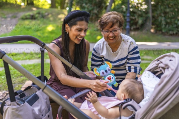 Grandmother, mother and baby girl enjoying time together at the park, mother feeding her baby solid