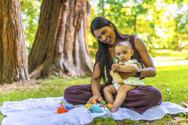 Latin mother and her baby daughter enjoying playtime with colorful toys on a blanket, under the