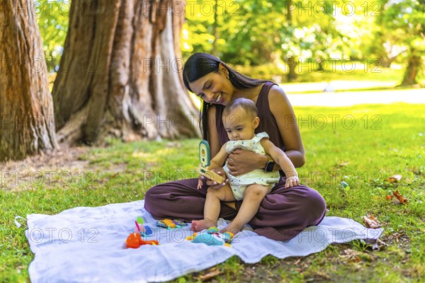 Latin mother and her baby daughter enjoying playtime with colorful toys on a blanket, creating a