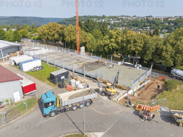 Aerial view of a construction site with large vehicles and active construction work, car park