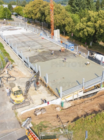 Workers and machines concreting on a construction site under a large crane, car park construction,