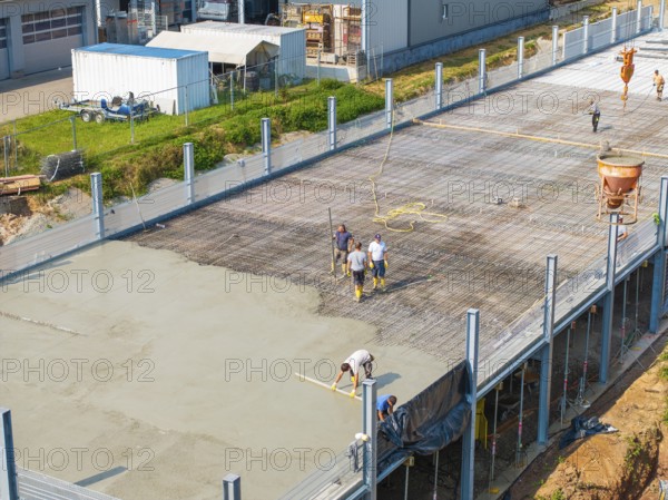 Construction workers working on a concrete surface on a building site in a green environment, car