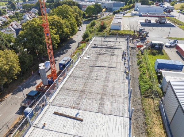 Crane over a construction site with workers and surrounding streetscape and landscape, car park