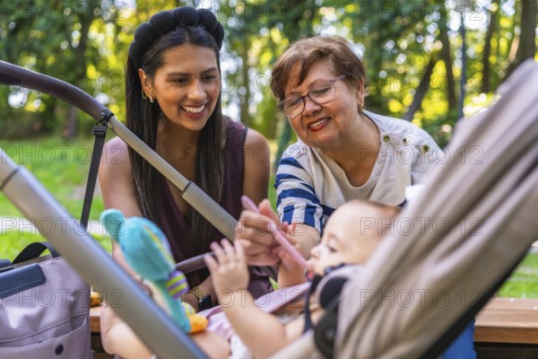 Grandmother lovingly feeding baby girl with a spoon while mother watches from the stroller in a