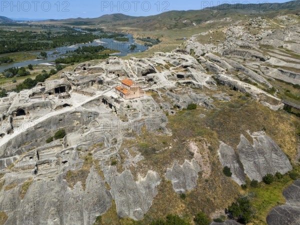 Historic cave town Uplistsikhe with impressive ruins in a green river landscape, aerial view, cave