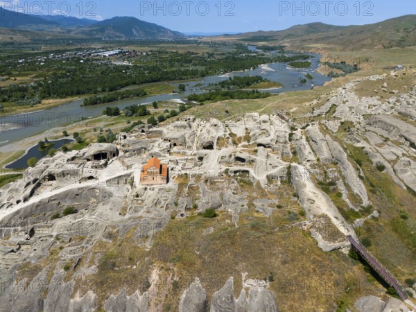 Panoramic view of a rocky landscape with embedded church and river view, aerial view, cave town