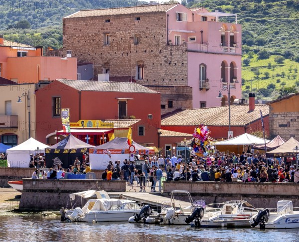 Sardinia, boats in the river Temo and residential buildings on the promenade, guests at the