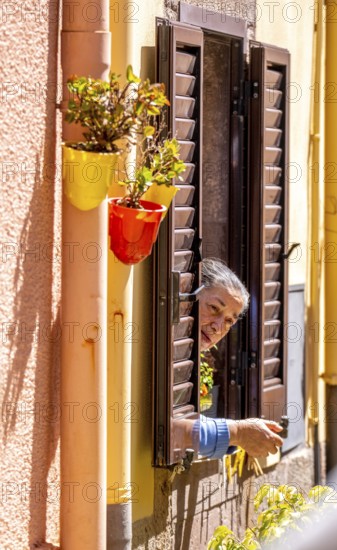 Sardinia, inhabitant looking out of a window, Bosa, Europe, Province of Oristano, Italy, everyday