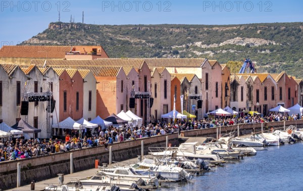 Sardinia, boats in the river Temo and houses on the promenade, guests at the restaurants with