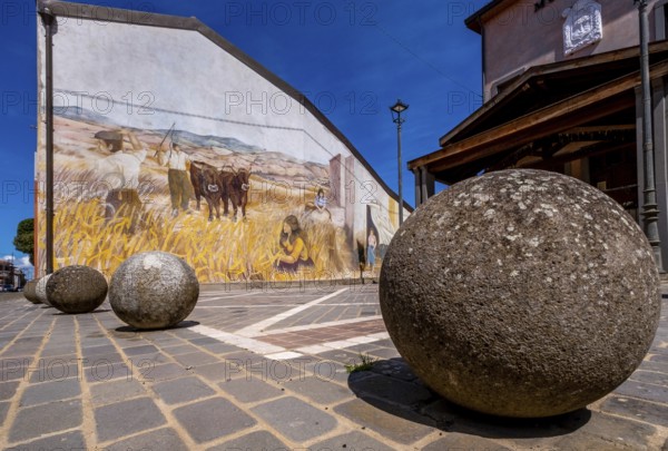 Sardinia, stone balls in front of a house with mural (Murales) Sardinia sight, Tinnura, Europe,