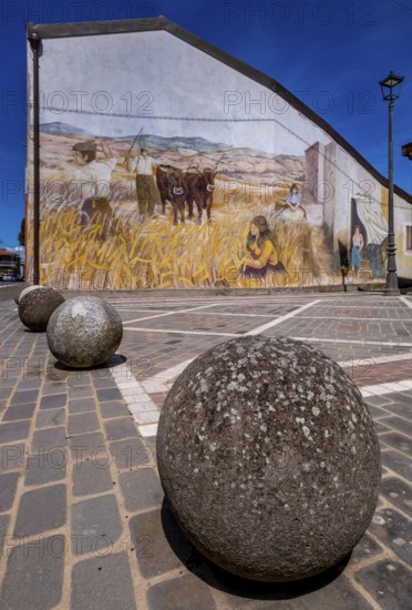 Sardinia, stone balls in front of a house with mural (Murales) Sardinia sight, Tinnura, Europe,