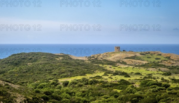 Sardinia, Former fortress tower, hilly coastal landscape by the sea, blue sky with clouds, Bosa,