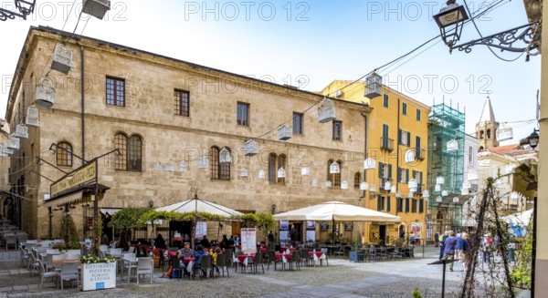 Sardinia, tourist tour group in the old town with sandstone-coloured palazzi, birdcage from house