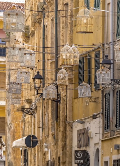 Sardinia, birdcage with light bulbs on power lines between houses above the alleyway, old town,