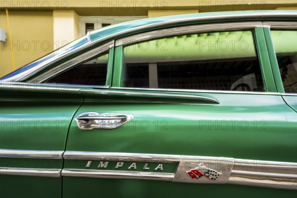 Vintage car, historic road cruiser, green Impala, streetlife in the city centre of Santa Clara at