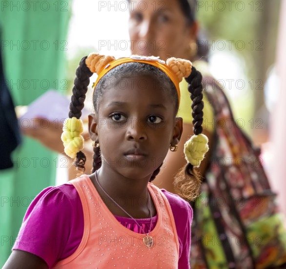 Young girl with pinned-up pigtails at a Cuban pizza stand with her family, Viñales, Cuba, Pinar del