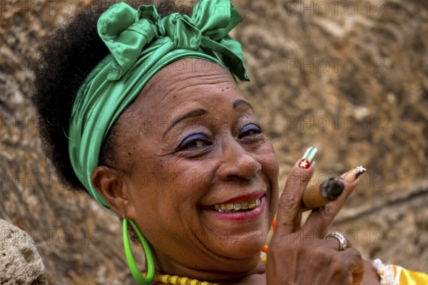 Old Cuban woman with green hair bow smokes a Havana cigar, Cuban woman with cigar and lacquered