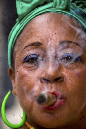 Old Cuban woman with green hair bow smokes a Havana cigar, Cuban woman with cigar and lacquered
