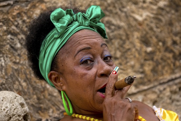 Old Cuban woman with green hair bow smokes a Havana cigar, Cuban woman with cigar and lacquered