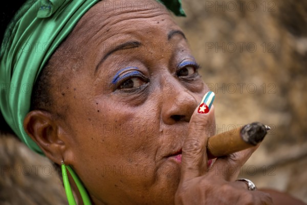 Old Cuban woman with green hair bow smokes a Havana cigar, Cuban woman with cigar and lacquered