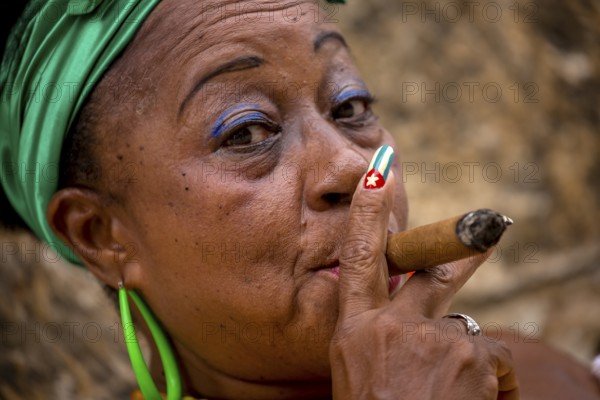 Old Cuban woman with green hair bow smokes a Havana cigar, Cuban woman with cigar and lacquered