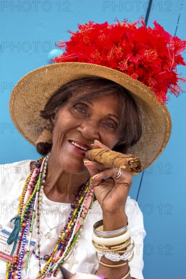 Old Cuban woman smokes a Cuban cigar on the street and posts with her cat for the tourists, La